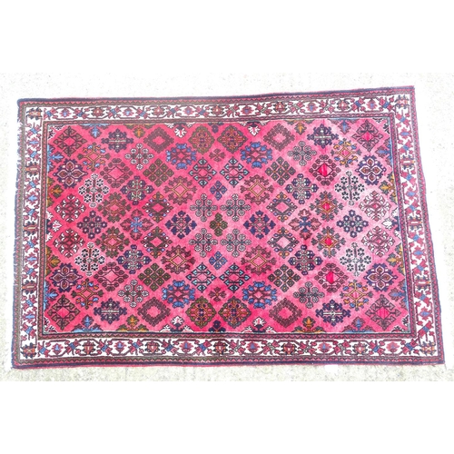 516 - Carpet / rug : a hand woven woollen rug with red central ground and 78 diamond shaped decorations to... 