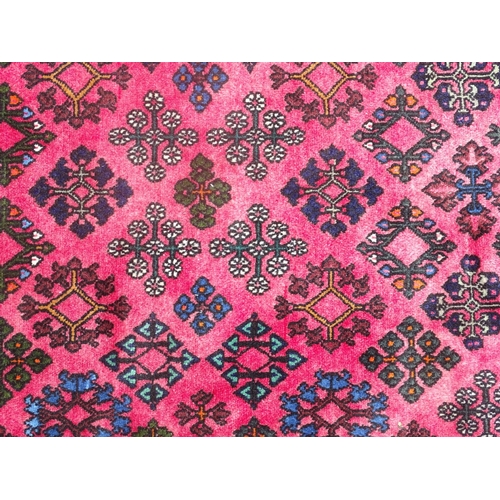 516 - Carpet / rug : a hand woven woollen rug with red central ground and 78 diamond shaped decorations to... 