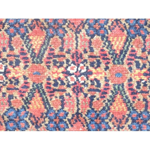 520 - Carpet / Rug : a hand woven Signed Runner with a red central ground, blue, navy blue, pink, black an... 