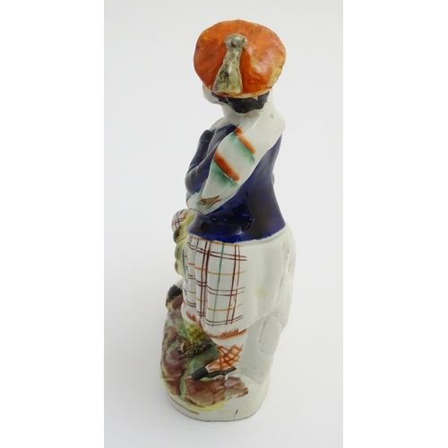 53 - A Victorian Staffordshire pottery figural group of a man and a woman in highland dress, he is wearin... 