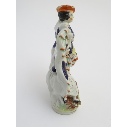 53 - A Victorian Staffordshire pottery figural group of a man and a woman in highland dress, he is wearin... 