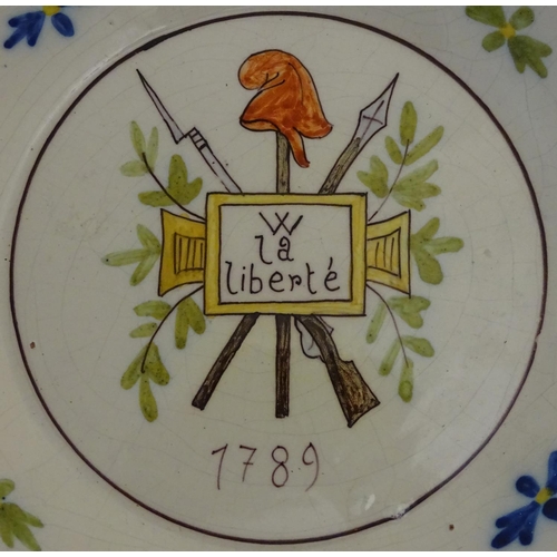 56 - Two French faience plates. One commemorating the French Revolution, decorated with a crossed bayonet... 