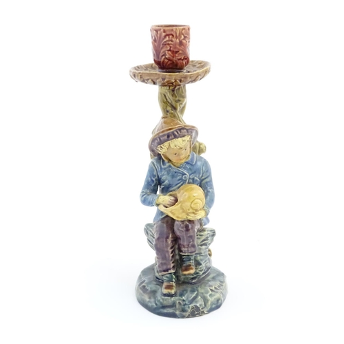 61 - A continental candlestick decorated with a fisherman boy holding a nautilus shell. Stamped under 'BD... 