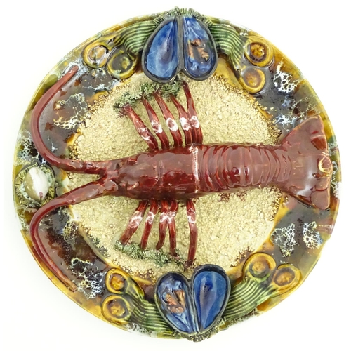 66 - A 20thC Portuguese Palissy style majolica dish with an applied model of a lobster on a bed of sand a... 