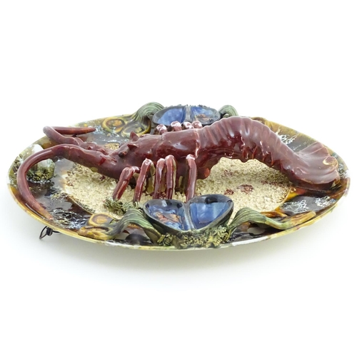 66 - A 20thC Portuguese Palissy style majolica dish with an applied model of a lobster on a bed of sand a... 