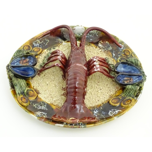 66 - A 20thC Portuguese Palissy style majolica dish with an applied model of a lobster on a bed of sand a... 