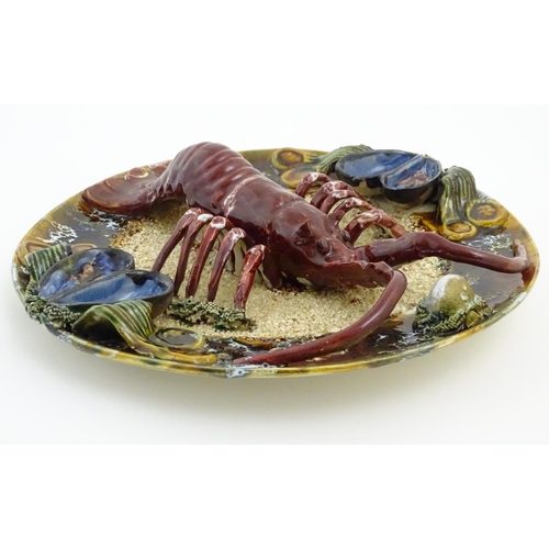 66 - A 20thC Portuguese Palissy style majolica dish with an applied model of a lobster on a bed of sand a... 