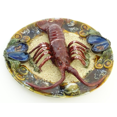 66 - A 20thC Portuguese Palissy style majolica dish with an applied model of a lobster on a bed of sand a... 