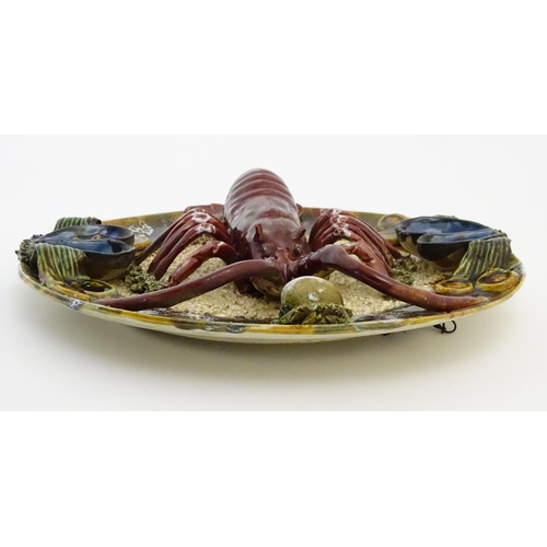 66 - A 20thC Portuguese Palissy style majolica dish with an applied model of a lobster on a bed of sand a... 