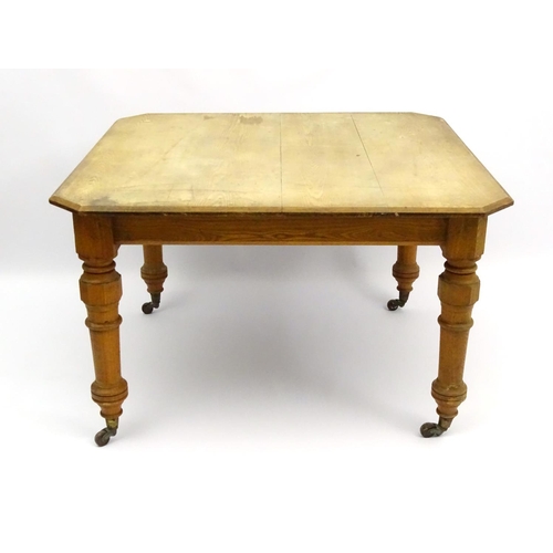 140 - An early 20thC ash dining table with chamfered and baluster turned legs terminating in ceramic casto... 