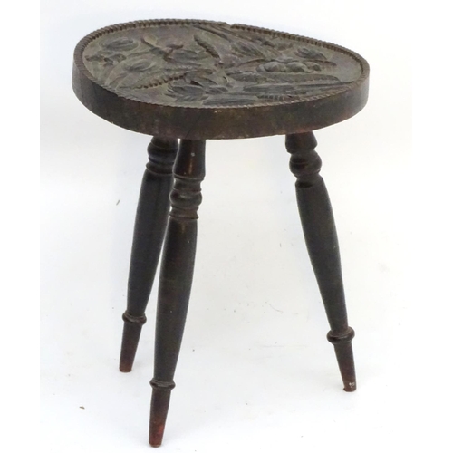 170 - A 19thC circular three legged stool with carved seat top, unusually depicting tad poles, and three t... 