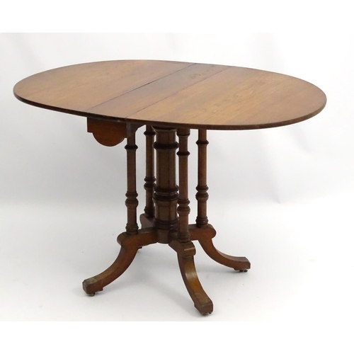 198 - An early 20thC walnut Sutherland table with central column surrounded by four turned supports, with ... 