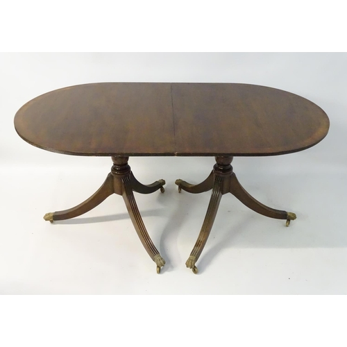 231 - An early 20thC mahogany Regency style dining table, with splayed fluted sabre legs terminating in br... 