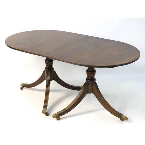 231 - An early 20thC mahogany Regency style dining table, with splayed fluted sabre legs terminating in br... 