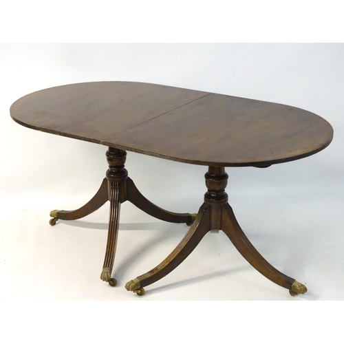 231 - An early 20thC mahogany Regency style dining table, with splayed fluted sabre legs terminating in br... 