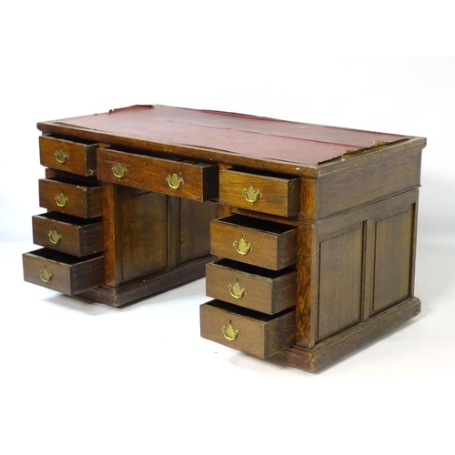 24 - An early 20thC oak pedestal desk comprising a single long central drawer flanked by four short drawe... 