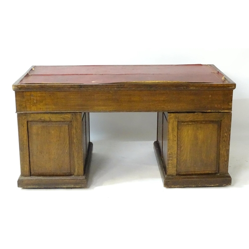 24 - An early 20thC oak pedestal desk comprising a single long central drawer flanked by four short drawe... 