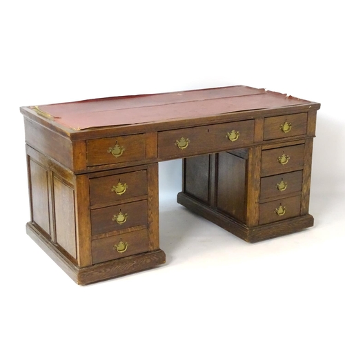 24 - An early 20thC oak pedestal desk comprising a single long central drawer flanked by four short drawe... 