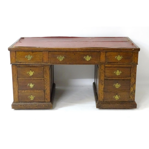 24 - An early 20thC oak pedestal desk comprising a single long central drawer flanked by four short drawe... 