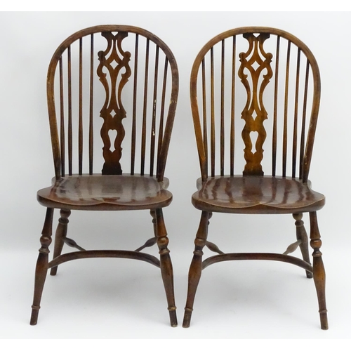 273 - A pair of early 20thC Windsor chairs with a wheelback and pierced central splat above a saddle seat ... 