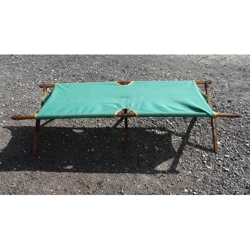 446 - A folding green canvas a wood campaign bed / camping bed