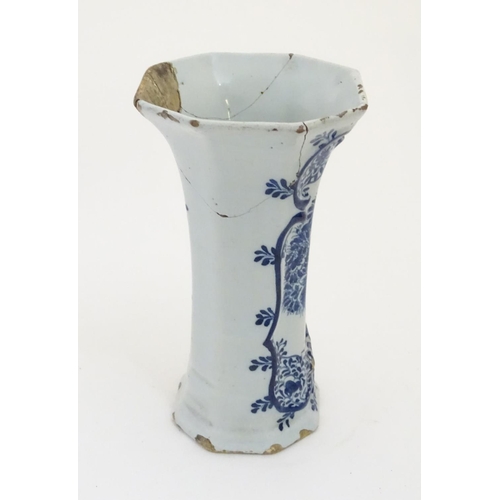 112 - An 18thC Delft blue and white octagonal vase with a flared rim, decorated with a vase of flowers and... 