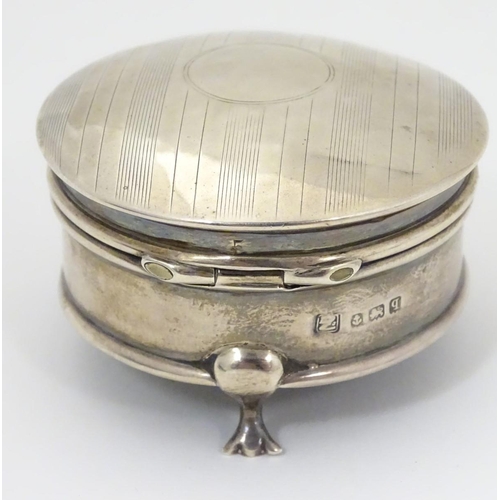 178 - A silver ring box with engine turned decoration and standing on three feet. Hallmarked Birmingham 19... 