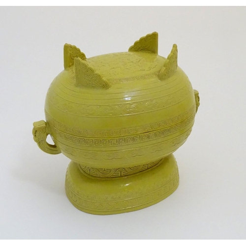 19 - A Chinese yellow ground lidded pot raised on a foot, with twin handles formed as stylised elephant h... 