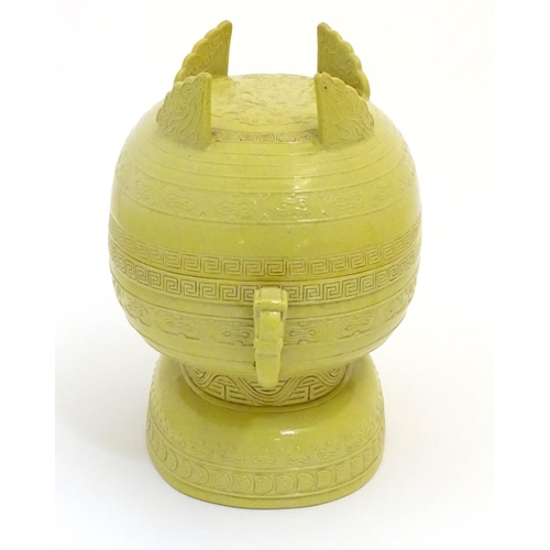 19 - A Chinese yellow ground lidded pot raised on a foot, with twin handles formed as stylised elephant h... 