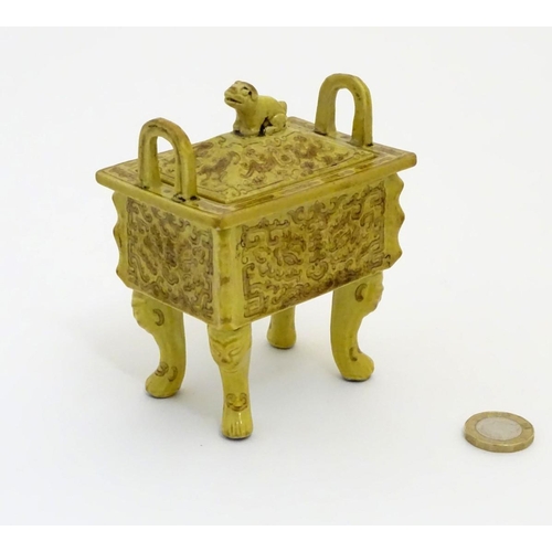 22 - A Chinese rectangular censer with a yellow ground, raised on 4 paw footed legs, with twin upright ha... 