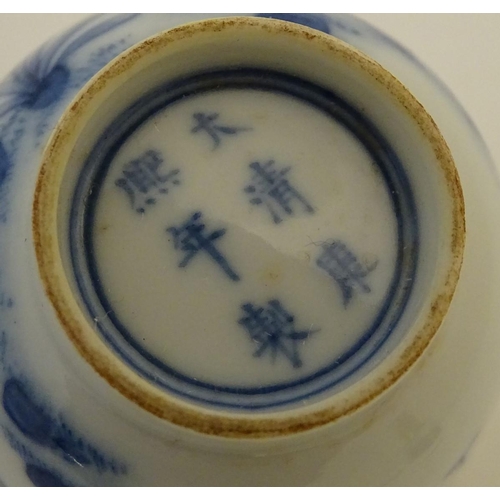 23 - A small Chinese blue and white cup decorated with flowers and Chinese script. Character marks under.... 