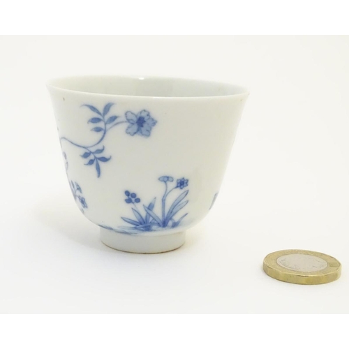 23 - A small Chinese blue and white cup decorated with flowers and Chinese script. Character marks under.... 