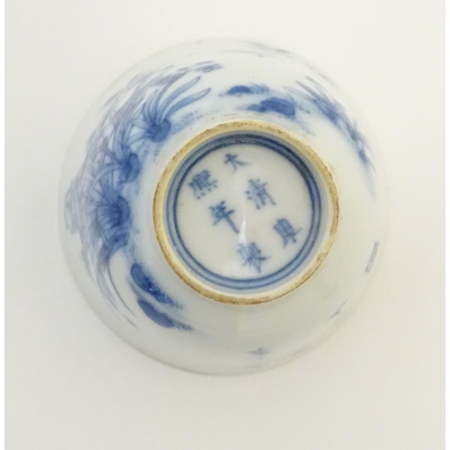 23 - A small Chinese blue and white cup decorated with flowers and Chinese script. Character marks under.... 