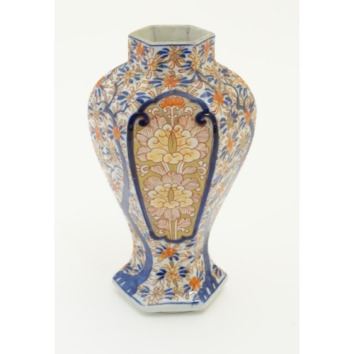 27 - An Imari style hexagonal vase with panelled floral decoration and gilt highlights. 7 1/2'' high.