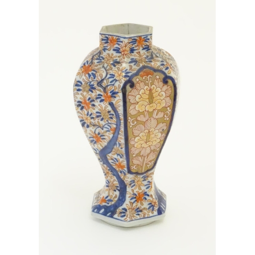 27 - An Imari style hexagonal vase with panelled floral decoration and gilt highlights. 7 1/2'' high.