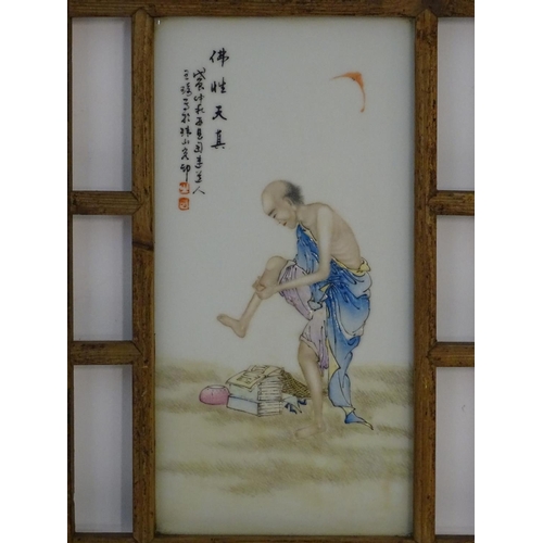 35 - A Chinese wooden wall hanging with an porcelain panel depicting a man with books at his feet. Chines... 