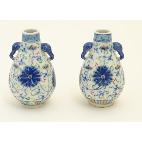 48 - A pair of Chinese miniature doucai baluster vases, decorated with flowers, with twin handles formed ... 