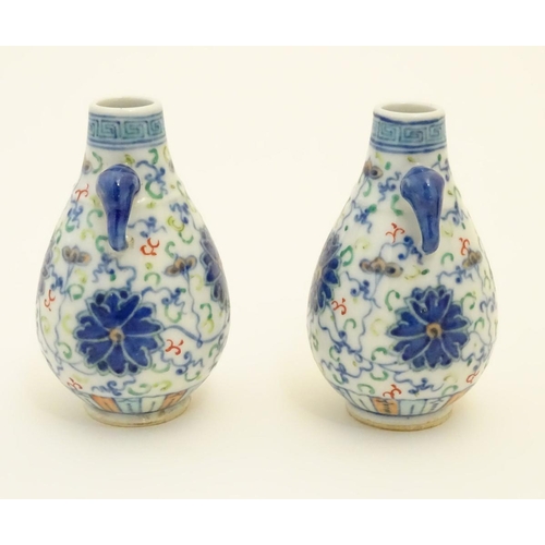 48 - A pair of Chinese miniature doucai baluster vases, decorated with flowers, with twin handles formed ... 