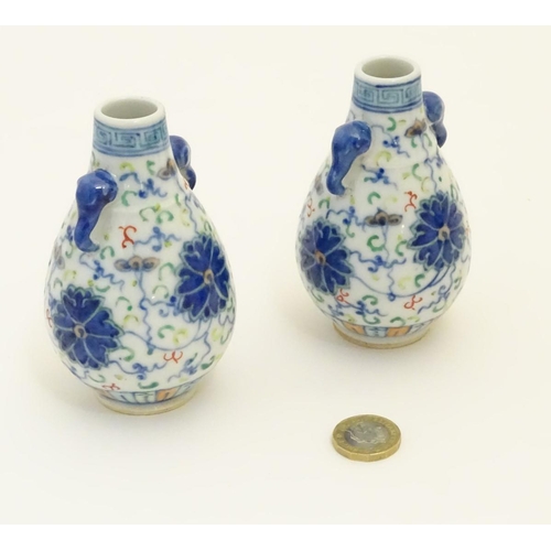 48 - A pair of Chinese miniature doucai baluster vases, decorated with flowers, with twin handles formed ... 