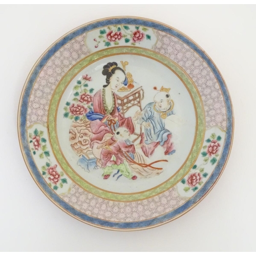 53 - A Chinese famille rose plate decorated with three figures in an interior, with a vase of flowers and... 