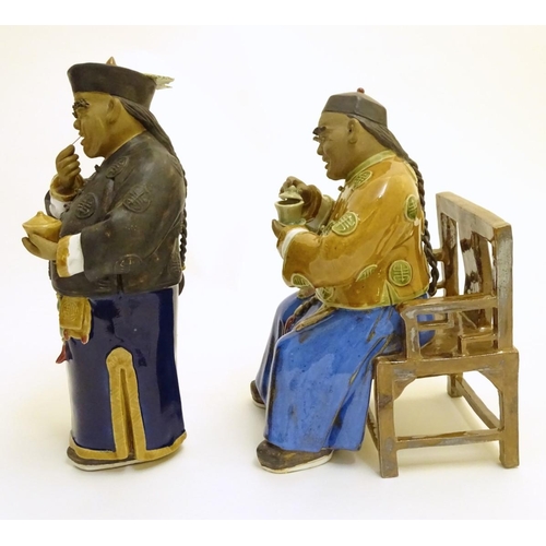 57 - Two ceramic figures of Chinese men in traditional dress drinking tea, one seated, the other standing... 