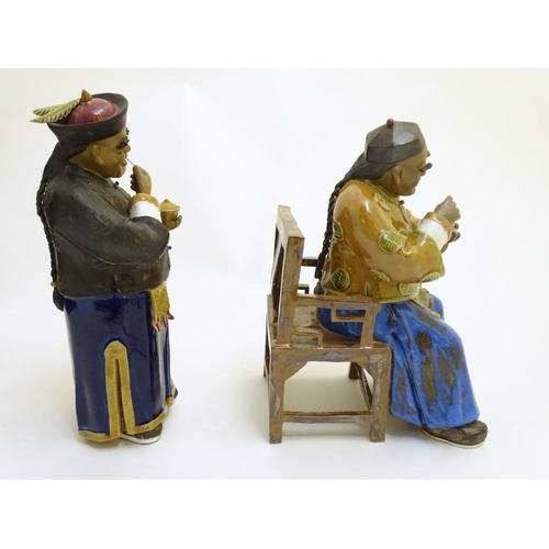 57 - Two ceramic figures of Chinese men in traditional dress drinking tea, one seated, the other standing... 