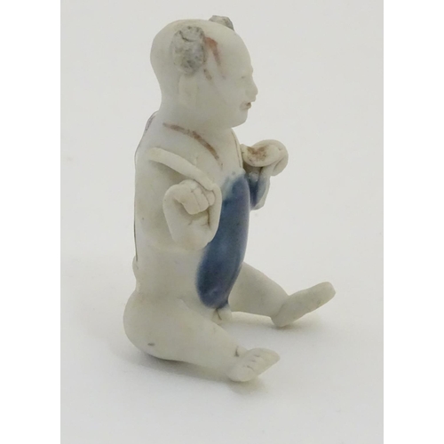 58 - An 18thC Chinese porcelain figure of a naked boy seated with his legs stretched forward and his arms... 