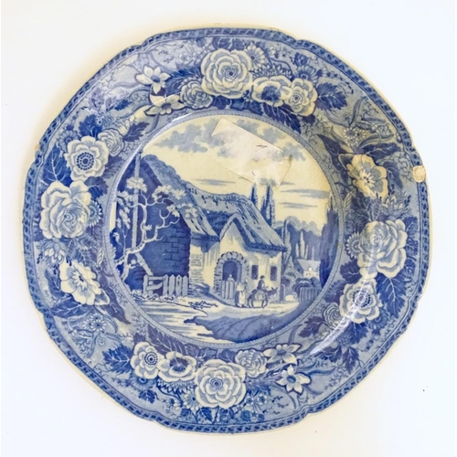 65 - A 19thC blue and white transferware plate depicting a country scene with a thatched cottage, figures... 