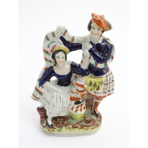 74 - A Victorian Staffordshire pottery figural group of a man and a woman in highland dress, he is wearin... 