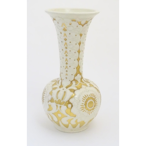 83 - A large cream Burmantofts Faience vase with an elongated neck and a flared rim, decorated with styli... 