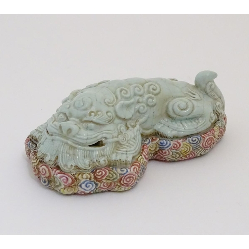 9 - A recumbent Chinese foo dog with a crackle glaze lying on a bed of stylised clouds. Character marks ... 