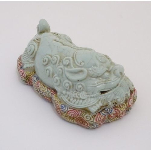 9 - A recumbent Chinese foo dog with a crackle glaze lying on a bed of stylised clouds. Character marks ... 