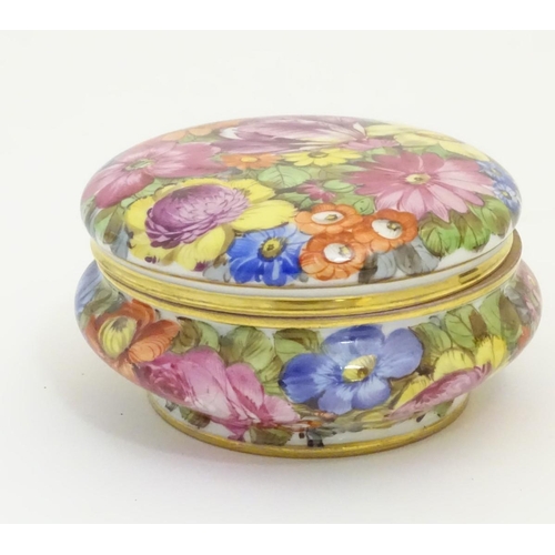 91 - A hand painted German powder bowl / lidded pot, decorated with colourful flowers, with a gilt rim an... 