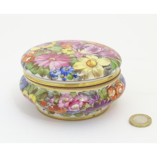 91 - A hand painted German powder bowl / lidded pot, decorated with colourful flowers, with a gilt rim an... 